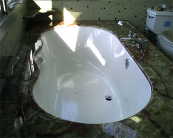 Private Residence, Orange County. This tub deck, fabricated from 2cm Dark Green Onyx, was designed to accommodate an undermount tub.  The hole is shaped and polished to conform to each individual tub