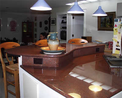 Private Residence, Raleigh. Texas Red granite was specified for this island to bring a little piece of Texas into the kitchen of Texas natives.  The asymmetric raised bar was designed by Prescott Stone at the request of the homeowner and there is a captured backsplash and a drop-in 