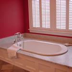 Private Residence, Chapel Hill. A vintage look drop-in tub was specified for this Chapel Hill master bath. The deck, of Carrara marble, has coordinating splashes to protect the adjacent walls. Use of such a design allows the bather to sit on the deck and easily swivel his or her legs in